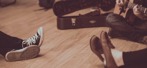 musicians sitting on the floor with a guitar